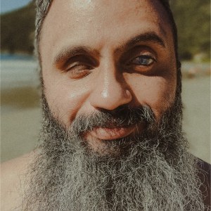 Foto de Alexandre Costa, homem de barba grisalha e cabelos curtos, sorrindo.